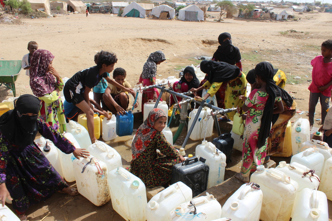 Des femmes vont à un point d'eau mis en place par Oxfam dans un camp au Yémen