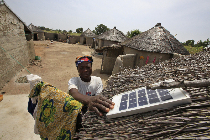 Une femme au Ghana regardant un panneau solaire sur une maison