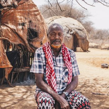 Wajir, Kenya- Feb 22, 2022. Ahmed Mohamud Omar, 70, sits in front of the home he shared with his wife who recently passed away due to thirst. Khadija Farah for Oxfam.