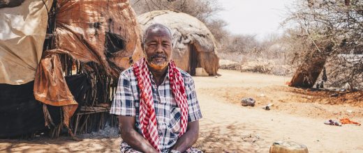 Sankuus*, 70, sits in front of the home he shared with his wife who recently passed away due to thirst.